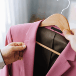 Una mujer sosteniendo un abrigo rosa colgado de un perchero.