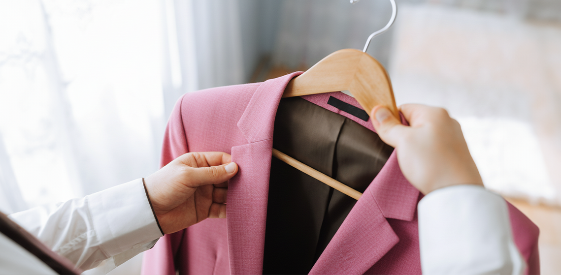 Una mujer sosteniendo un abrigo rosa colgado de un perchero.