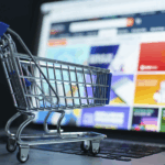 Fraude amistoso: carrito de compras en miniatura sobre un teclado de laptop.