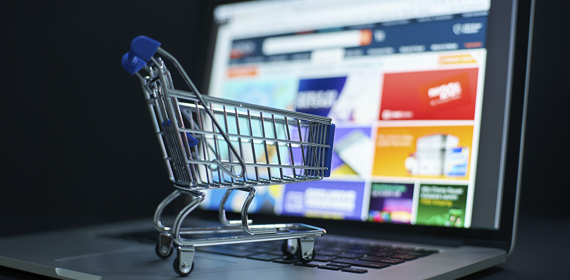 Fraude amistoso: carrito de compras en miniatura sobre un teclado de laptop.